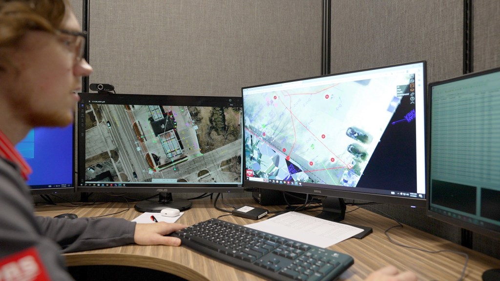 A CAD technician working on a 3D utility file rendering at a computer