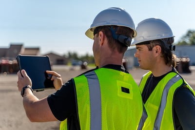 Two Construction workers viewing construction site with SiteMap displaying on tablet.