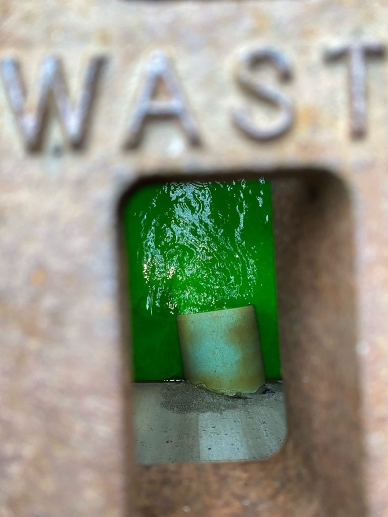 View from a storm grate of bright green dye flowing through a storm drain.