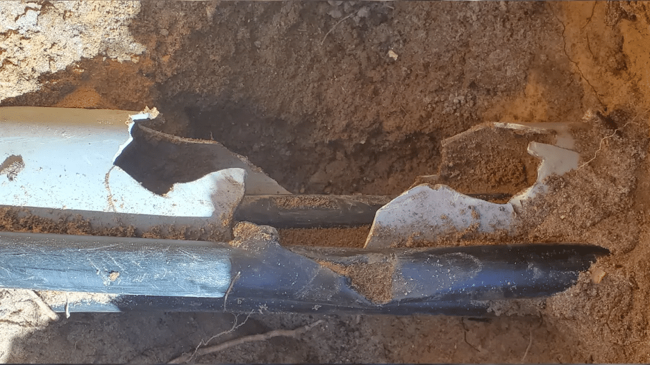 A damaged conduit partially unearthed.