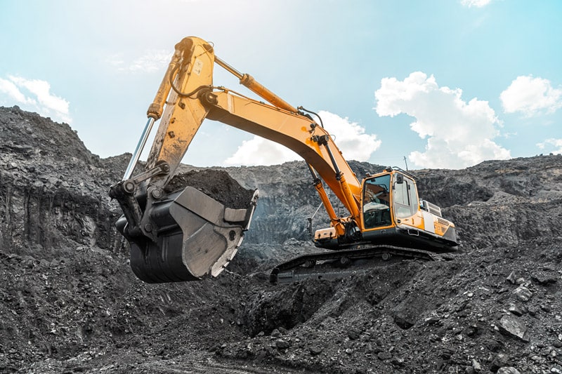 An excavator scooping dirt out of a large hole.