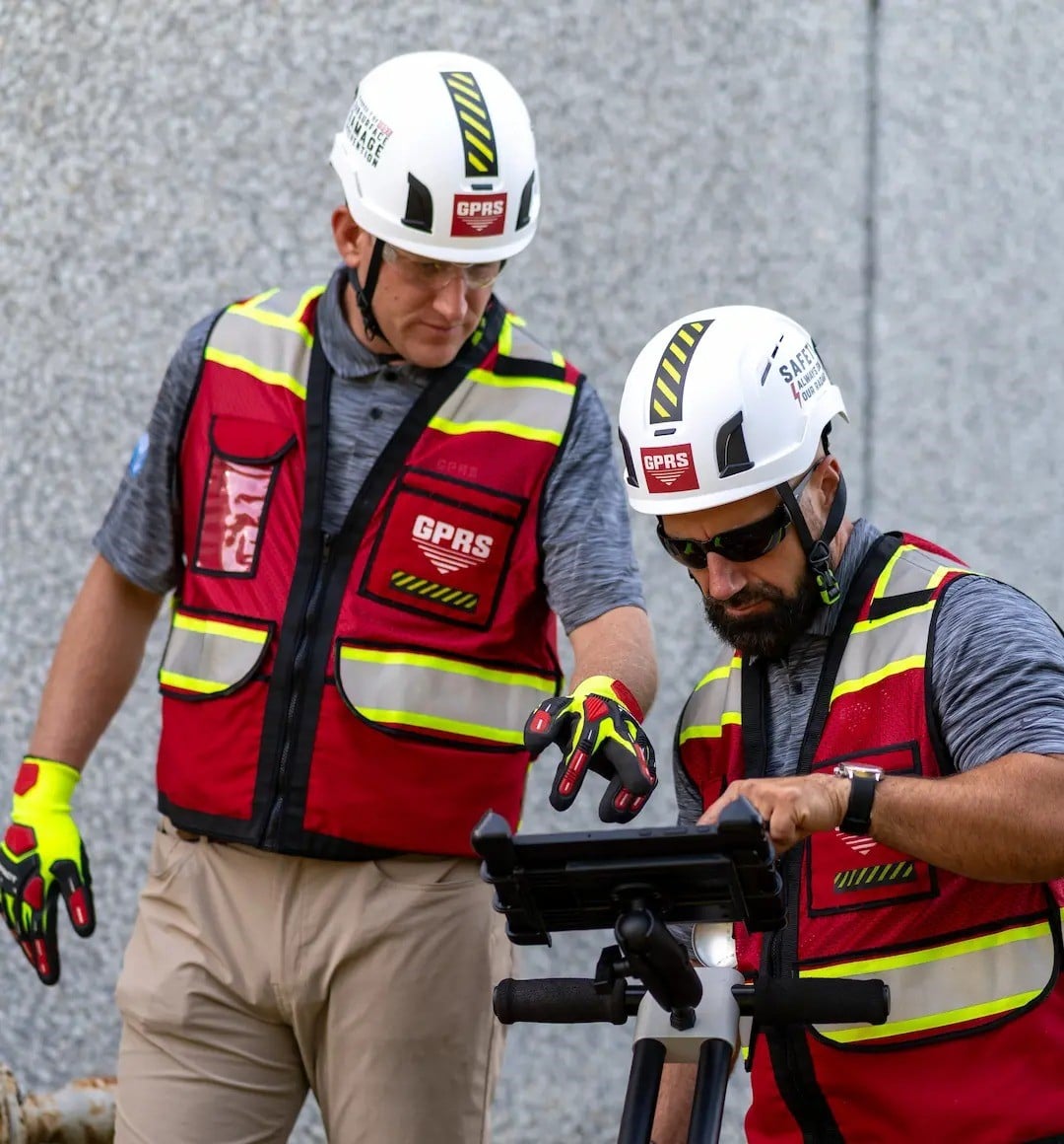 Two GPRS Project Managers looking at the screen on a ground penetrating radar utility locating cart.