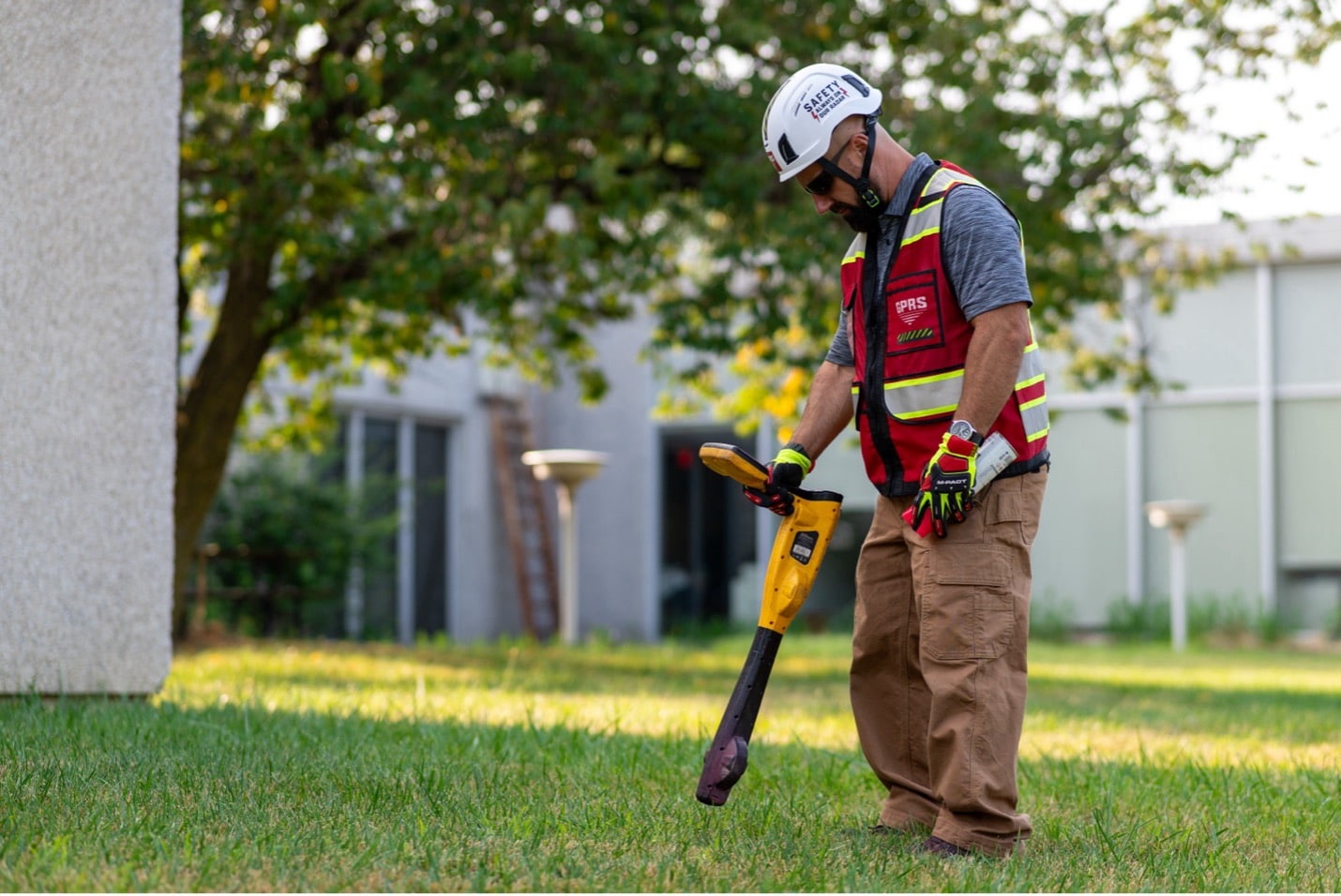 GPRS Project Manager runs an electromagnetic locator over a grassy field.