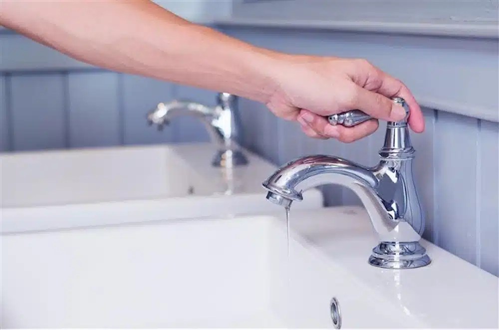 A hand turning a faucet.