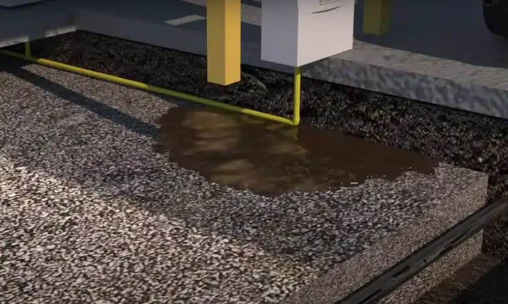 Computer-generated animation of gasoline leaking out of a line under a gas station pump.