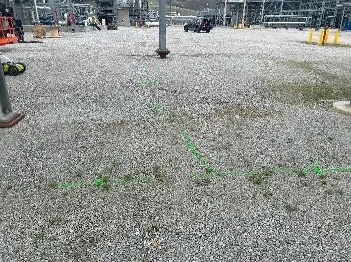 A gravel field with green spray paint indicating the location of an electrical ground line.
