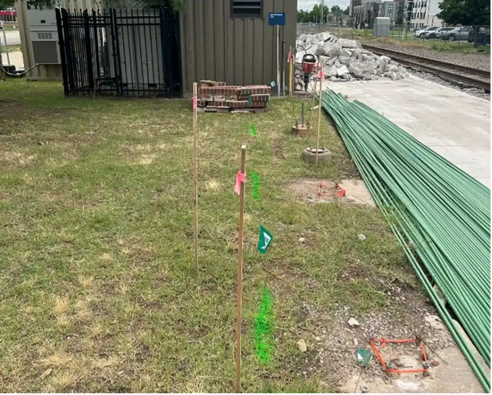Green spray paint on a grassy area next to cement and train tracks.