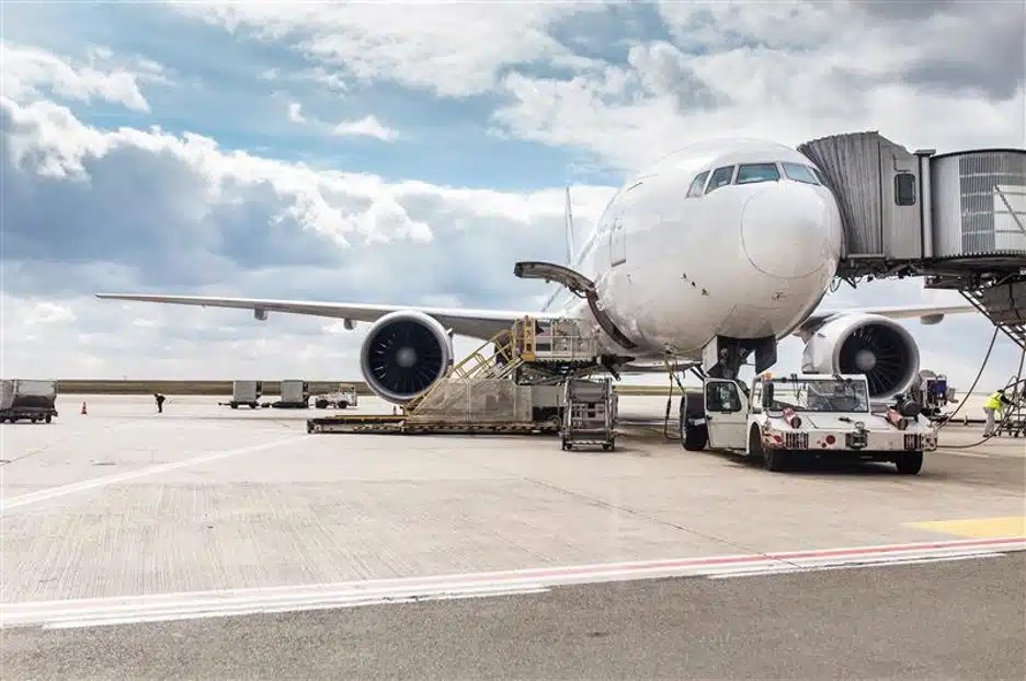 A commercial airplane at a terminal on a runway.